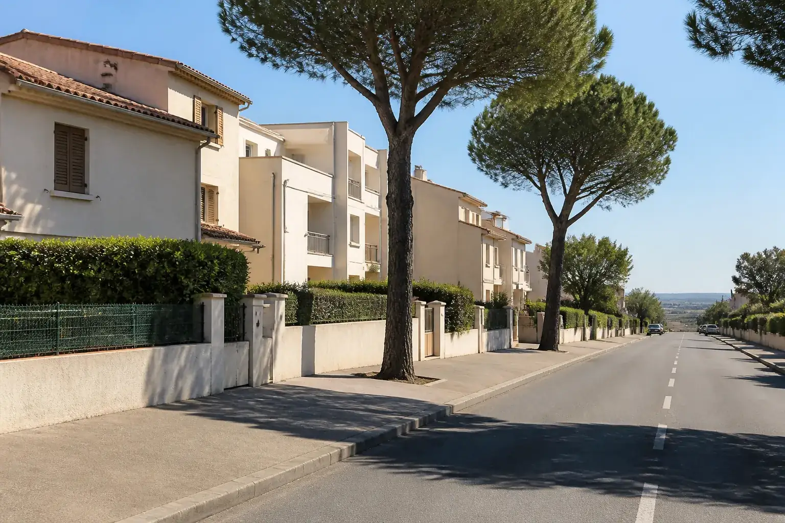 Rue de couronne au front bâti discontinu, petits collectifs et maisons accolées, murets bas et trottoir large